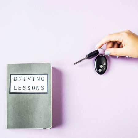 Female hands hold the car keys. Next to the study notebook for driving lessons. Getting a driving...