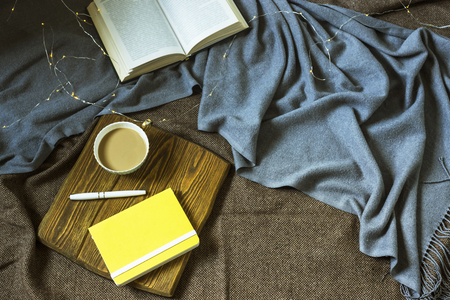 A cup of coffee and a notepad on a wooden stand for plihaad. Work and rest in a cozy home environment in winter or autumn. Top view, flat layの写真素材