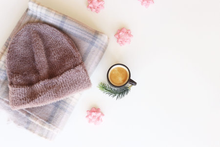 Women's winter accessories - hat and scarf next to a cup of coffee and bows to decorate Christmas...