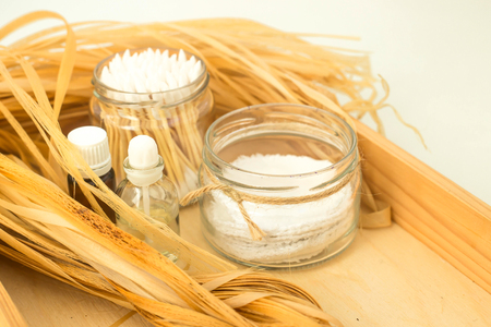Eco accessories for body care and spa - bast, loofah, wooden cotton swabs in a glass jar, essential and aroma oil on a wooden tray. Zero waste conceptの写真素材