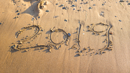 2019 - the date of the new year is written on the yellow sand by the sea or ocean. The concept of the New Year holidays and the onset of the new year twenty nineteen. Backgroundの写真素材
