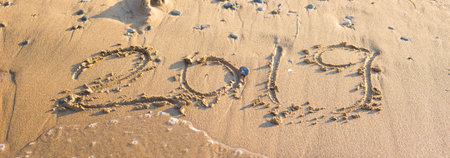 2019 - the date of the new year is written on the yellow sand by the sea or ocean. The concept of the New Year holidays and the onset of the new year twenty nineteen. Backgroundの写真素材