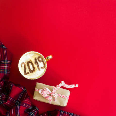 New Year 2019 is written on a cup of coffee with milk. The concept of the new year on January 1. On a red background with a gift. Top view, flat lay, copy spaceの写真素材