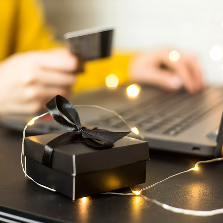 Black gift box - shopping online through a laptop with a credit card. A girl makes a purchase from home via the Internet. Cyber monday and black friday conceptの写真素材