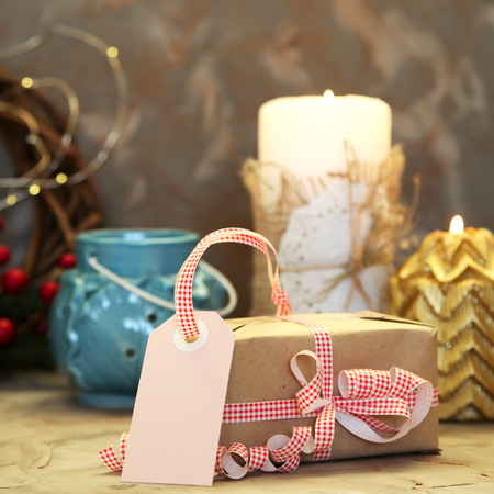 Label for the signature of a Christmas gift decorated with red and white ribbon among Christmas candles and lightsの写真素材