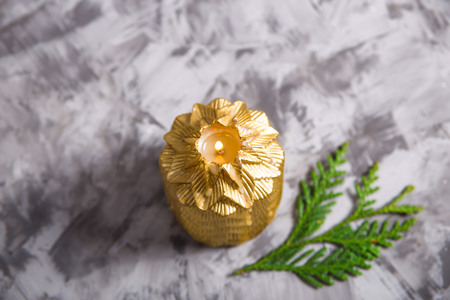 Golden Christmas candle in which the fire is burning on a gray background next to the green branches of a thuja or Christmas tree. Top viewの写真素材