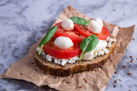 Beautiful healthy snack - sandwich with tomato, mozzarella and spinach leaves. Vegetarian food conceptの写真素材