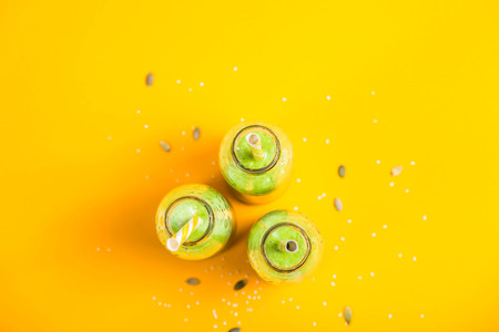 Green smoothies in three glass bottles with tubes on a bright yellow background. Healthy food detox concept. Top view, flat lay, copy spaceの写真素材