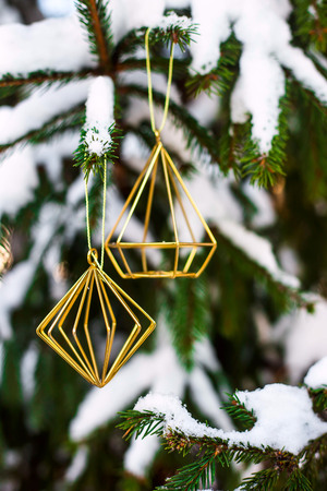 The branches of the Christmas tree covered with snow outdoor decorated with gold metal minimalist figures. Winter background conceptの写真素材