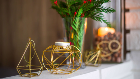 Home winter Christmas decorations in the apartment - candlesticks, a vase with green branches and red berries, golden figuresの写真素材