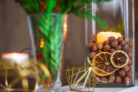 Home winter Christmas decorations in the apartment - candlesticks, a vase with green branches and red berries, golden figuresの写真素材