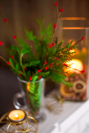 Home winter Christmas decorations in the apartment - candlesticks, a vase with green branches and red berries, golden figures. Blurred image,
backgroundの写真素材