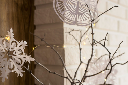 Self-made paper snowflakes are fixed on sticks of a tree as a winter Christmas decoration of an apartment. Minimalismの写真素材