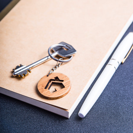 The keys to the new apartment with a wooden key chain house on a black table next to the crafting...