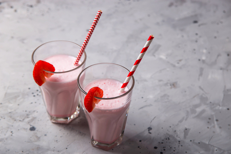 Two glasses with strawberry milkshake with pieces of berries on the edge of the glassの写真素材