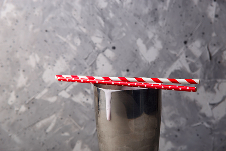 Metal capacity of a shaker for a milkshake with a flowing down strawberry cocktail and tubules on topの写真素材