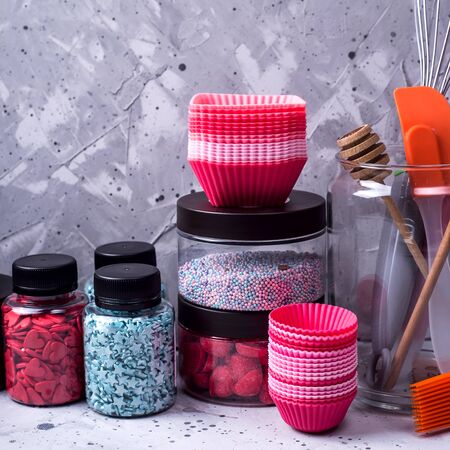 Tools for making desserts and sweets - powders and decorations, spoons, muffin molds, icing. On a gray backgroundの写真素材