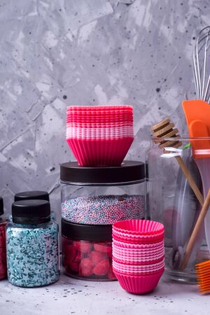 Tools for making desserts and sweets - powders and decorations, spoons, muffin molds, icing. On a gray backgroundの写真素材