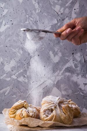 Sweet fresh puff pastry onto which the sifter icing powder is pouredの写真素材