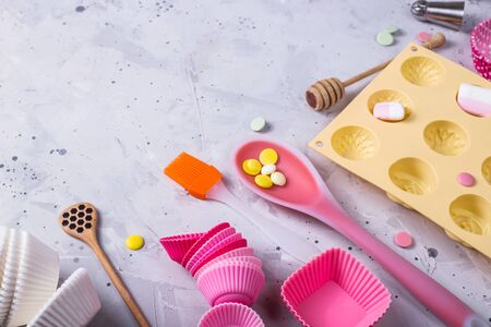 Tools for making desserts and sweets - powders and decorations, spoons, muffin molds, icing. On a gray background. Top view, flat lay. Copy spaceの写真素材