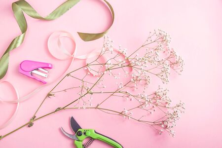 Florist tools for creating bouquets and caring for flowers - pruner and stapler with flowers on a pink tableの写真素材