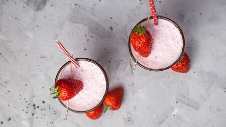 Strawberry milkshake in two transparent glasses decorated with chocolate and ripe red strawberries. Top view, flat layの写真素材