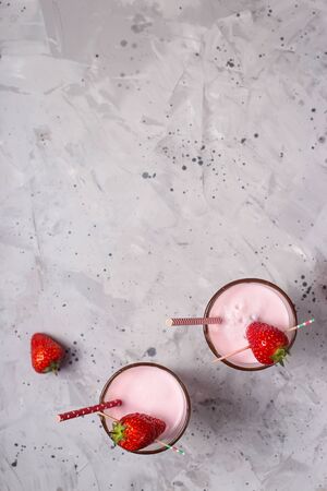 Strawberry milkshake in two transparent glasses decorated with chocolate and ripe red strawberries. Top view, flat lay. Copy spaceの写真素材