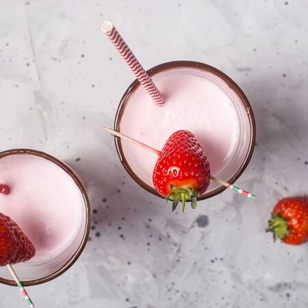 Strawberry milkshake in two transparent glasses decorated with chocolate and ripe red strawberries. Top view, flat layの写真素材