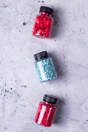 Three transparent bottles with sugar hearts and asterisks for decorating pastry on a gray table. Top view, flat layの写真素材