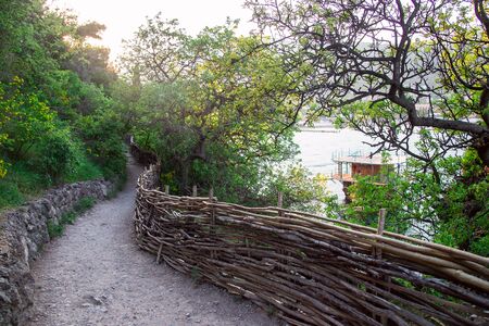 Small fishing house on stilts near the sea and a path among the mountains and greenery. Beautiful landscapeの写真素材