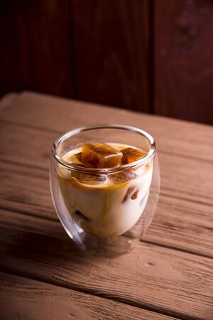 Cubes of iced coffee with milk in a modern glass with double glass. Close upの写真素材