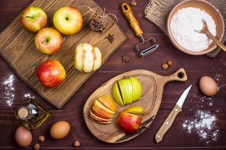Sliced apples on a wooden board among the products for making apple pie or other baking. Autumn food concept. Top view, flat layの写真素材