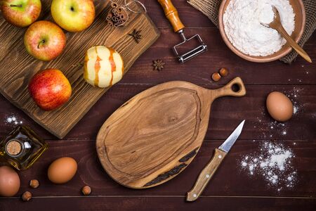 Empty board for slicing apples and making a cake among the ingredients for baking. Autumn food concept. Top view, flat lay, copy spaceの写真素材