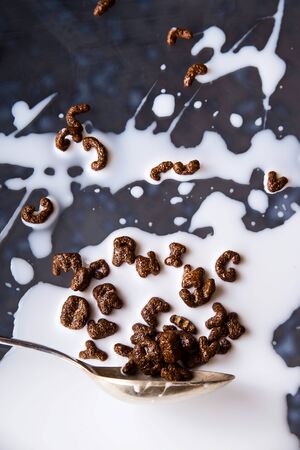 Chocolate cornflakes in the shape of letters of the English alphabet for a quick breakfast with milk on a gray backgroundの写真素材