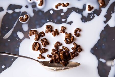 Chocolate cornflakes in the shape of letters of the English alphabet for a quick breakfast with milk on a gray backgroundの写真素材