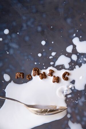The word morning is written with chocolate cornflakes for a quick breakfast with milk on a gray background with levitationの写真素材