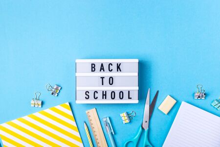 Bright modern minimalist stationery for school on a blue background next to a decorative lamp with the inscription back to schoolの写真素材