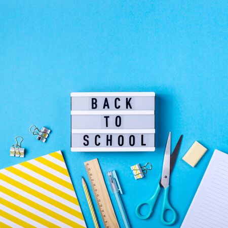 Bright modern minimalist stationery for school on a blue background next to a decorative lamp with the inscription back to schoolの写真素材