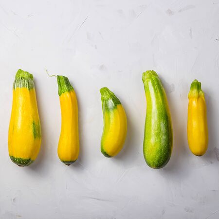 Yellow ripe zucchini on gray textured background - autumn harvest concept in minimalism styleの写真素材