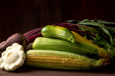 Autumn agricultural harvest with corn and other vegetables on a wooden tableの写真素材
