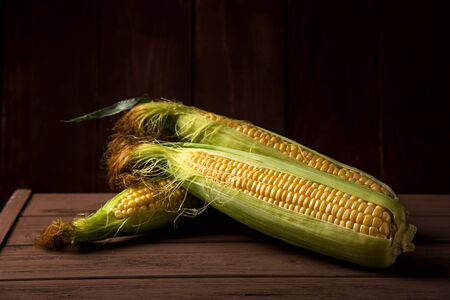Corn on a wooden dark table - autumn harvest concept and thanksgiving product for a holidayの写真素材