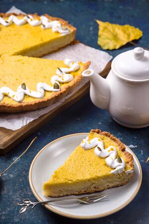 Traditional pumpkin pie with pumpkin twigs on a blue table for a family Thanksgiving partyの写真素材