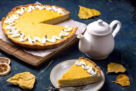 Traditional pumpkin pie with pumpkin twigs on a blue table for a family Thanksgiving partyの写真素材