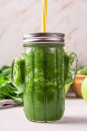 Green smoothie in a cactus shaped glass among the green ingredients of apples, spinach, avocado and parsley. Healthy raw food and detox conceptの写真素材
