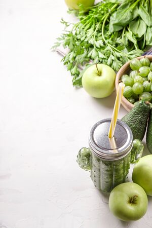 Green smoothie in a cactus shaped glass among the green ingredients of apples, spinach, avocado and parsley. Healthy raw food and detox concept. Copy spaceの写真素材