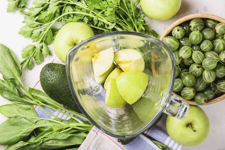Ingredients for making healthy green smoothies made from apples, spinach, avocado and parsley around a blender glass bowl. Top view. flat layの写真素材