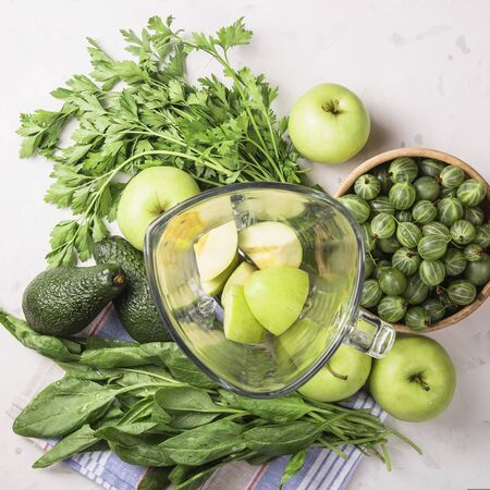 Ingredients for making healthy green smoothies made from apples, spinach, avocado and parsley around a blender glass bowl. Top view. flat layの写真素材