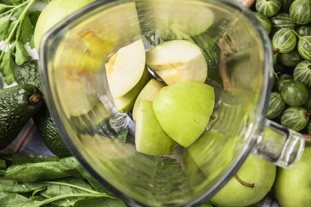 Ingredients for making healthy green smoothies made from apples, spinach, avocado and parsley around a blender glass bowl. Top view. flat layの写真素材