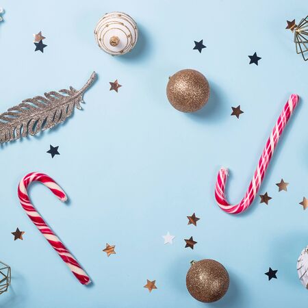 Christmas minimalist layout on a bright blue background with red-white candies and festive glittery decorations. Top view, flat lay, copy spaceの写真素材