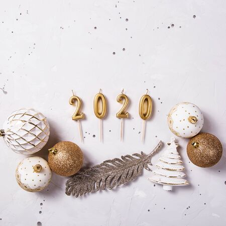 Golden candles in the shape of numbers 2020 as a symbol of the new year next to golden holiday decorations on a gray table. Top view, flat layの写真素材